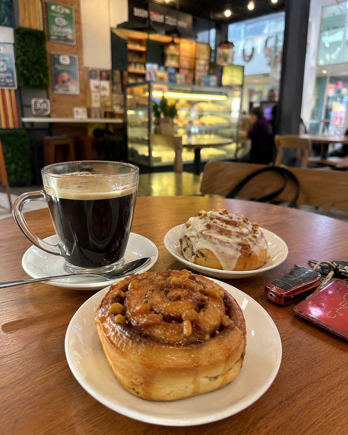 Two cinnamon rolls with glazed frosting and nuts, served with black coffee at Annipie Davao